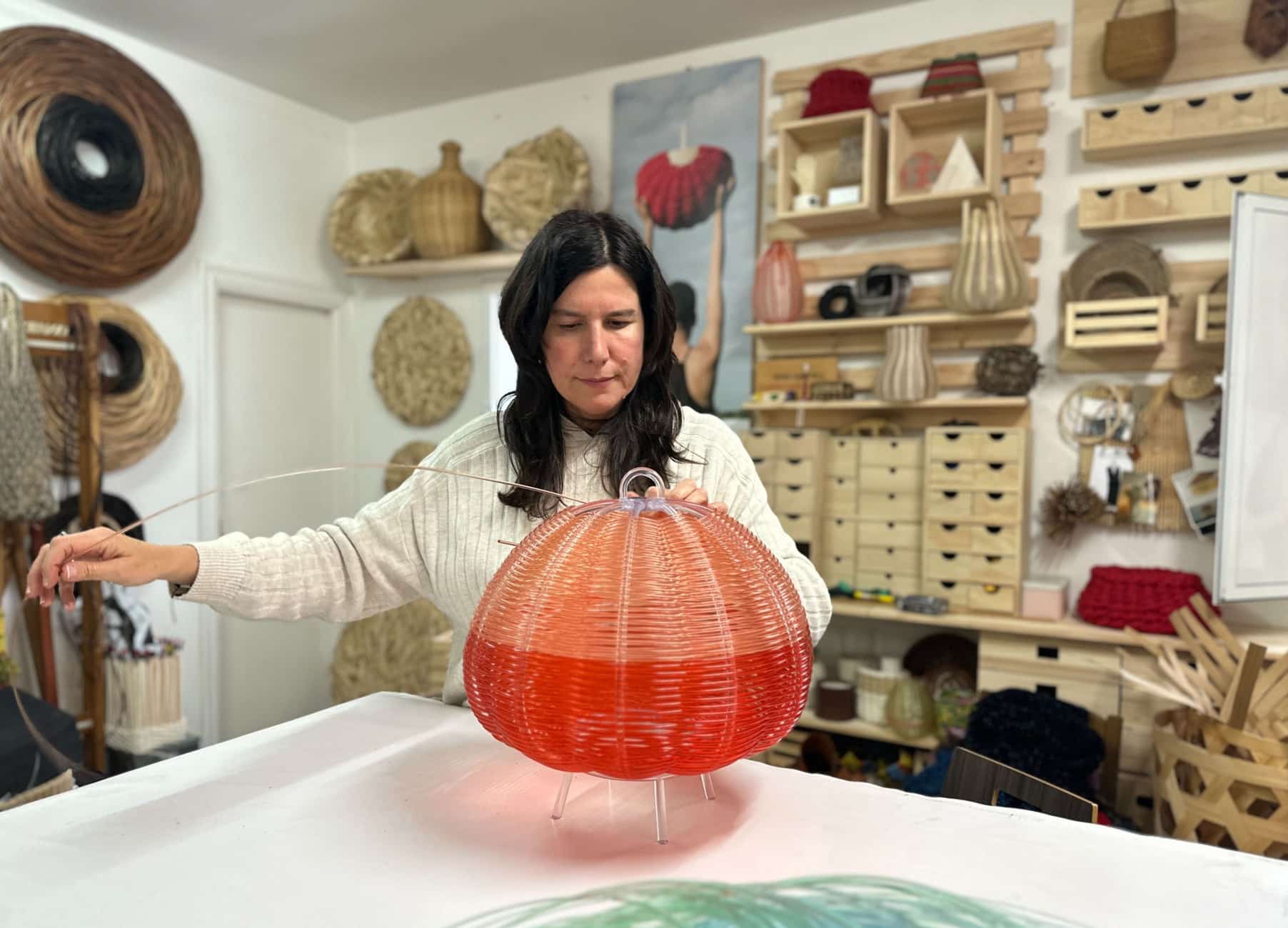 Colorful woven paper lantern being crafted by an artist in a creative workspace.