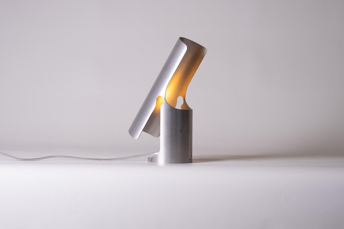 Sleek modern desk lamp with warm yellow lighting on a minimalist white background.