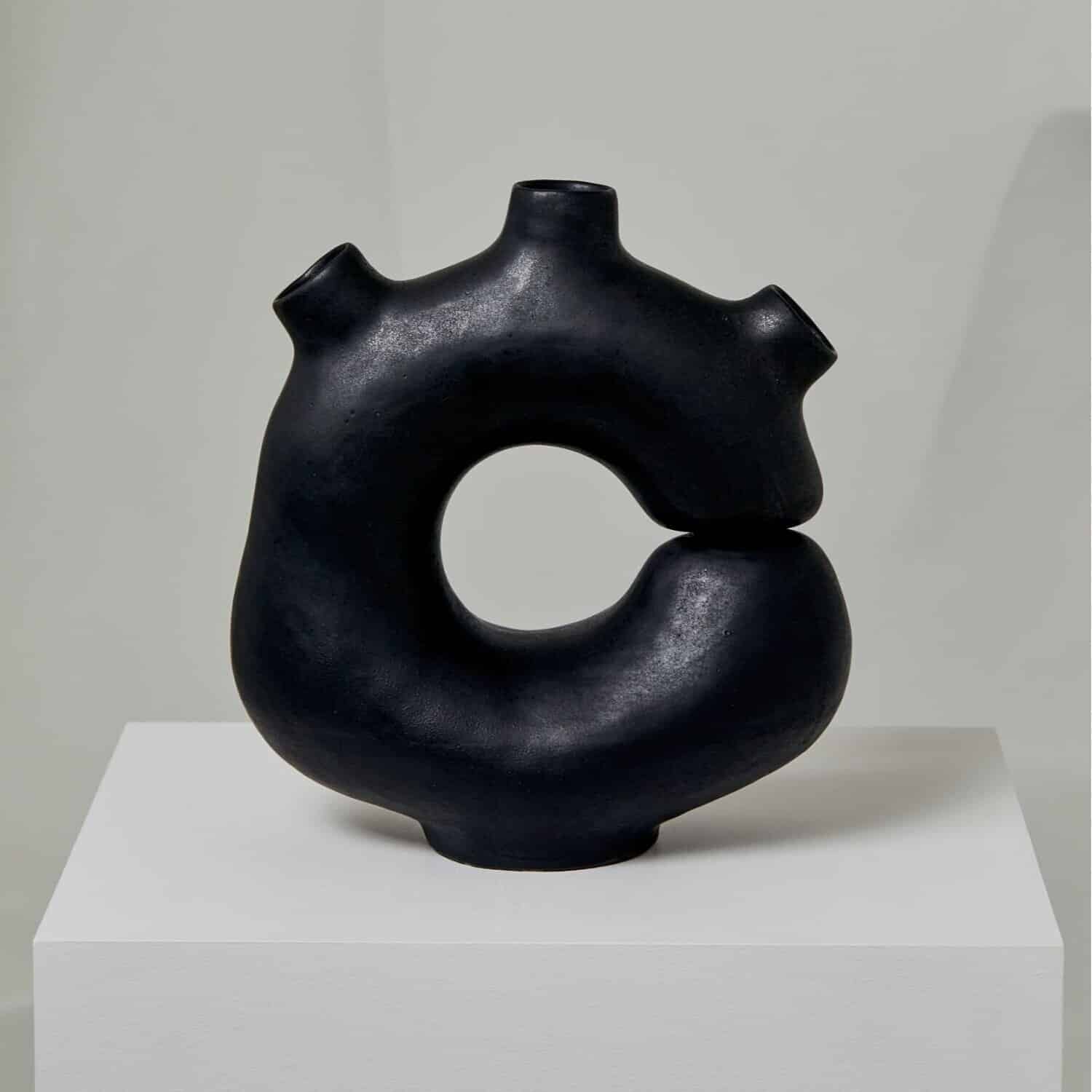 Contemporary black ceramic sculpture with a circular form and abstract design.