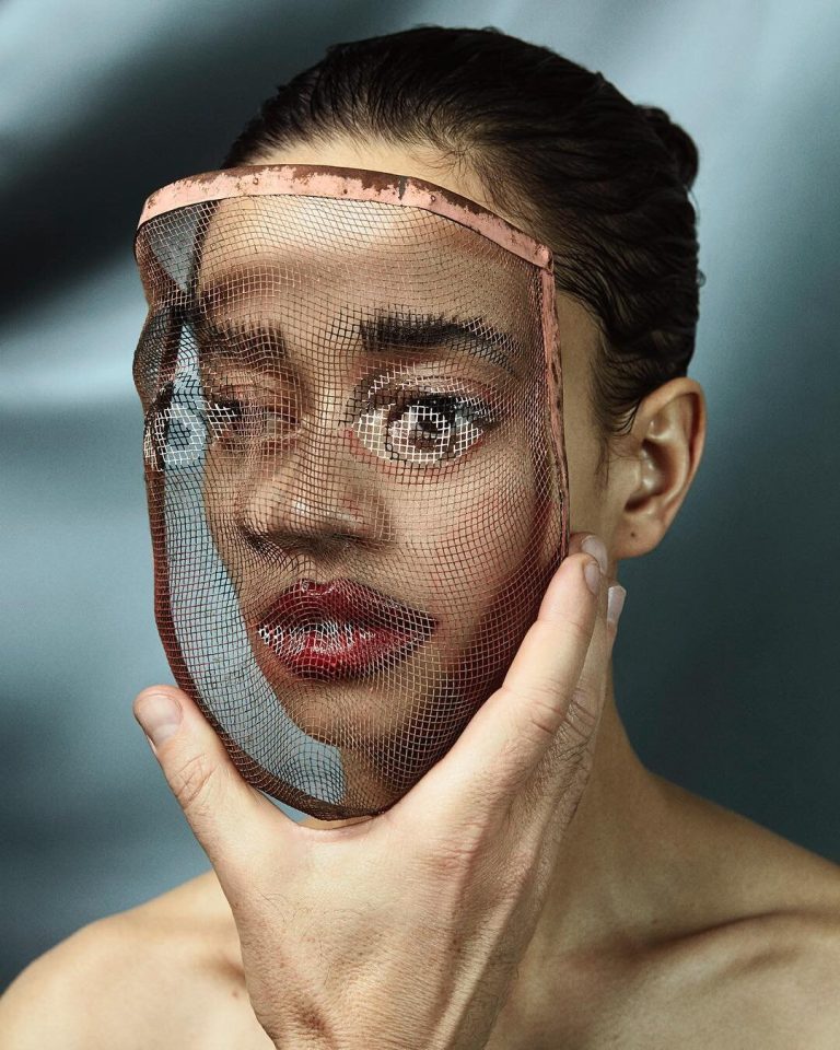 Interview with Katja Mayer Intricate portrait of a woman holding a mesh face mask, highlighting artistic makeup and modern fashion photography.