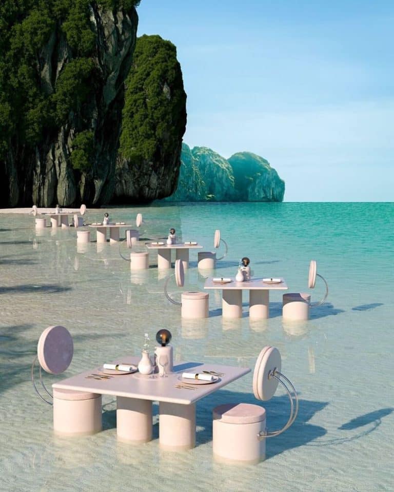Interview with Paul Milinski Elegant outdoor dining setup on pristine beach with modern furniture and scenic limestone cliffs.