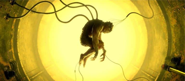 "Rebirth" Questions The Capabilities Of Manipulation Eerie figure with wires inside a circular, yellow-lit space, creating a futuristic, dystopian atmosphere.