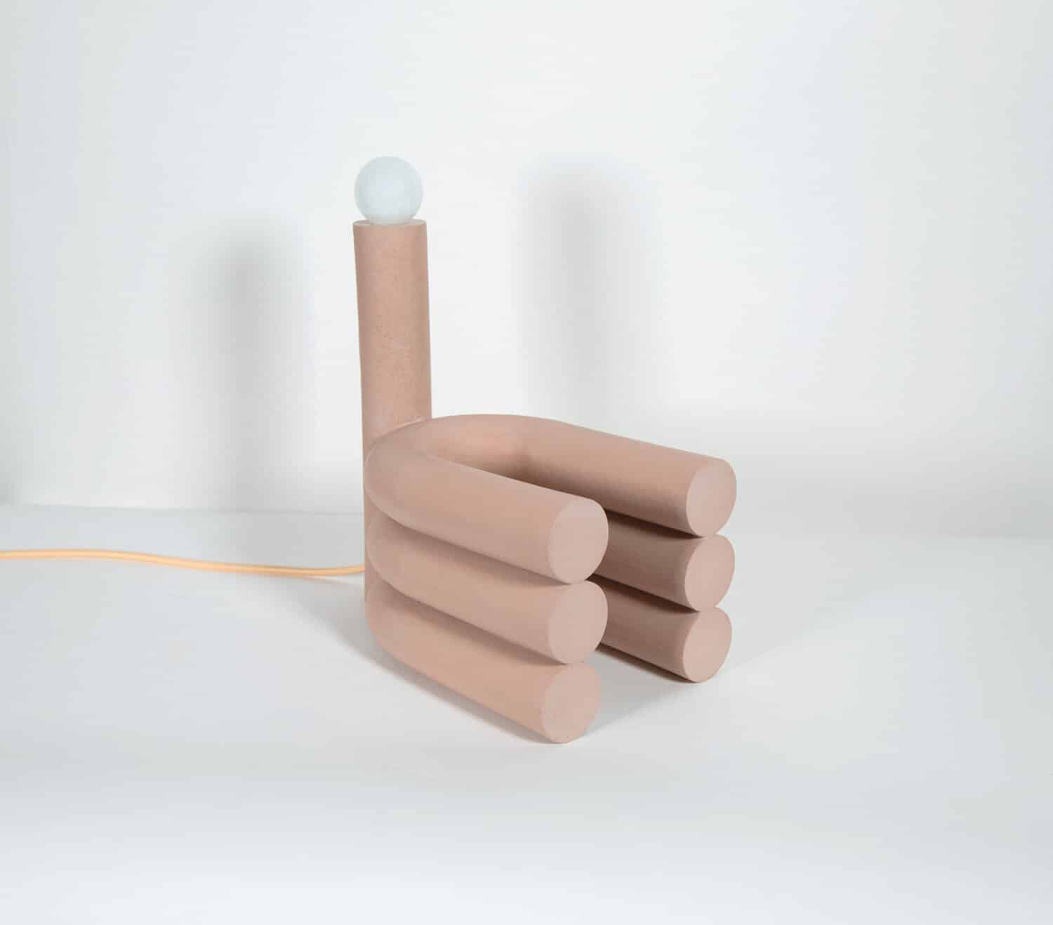 Soft pink minimalist table lamp with cylindrical shapes and a white globe on top, modern and stylish design.