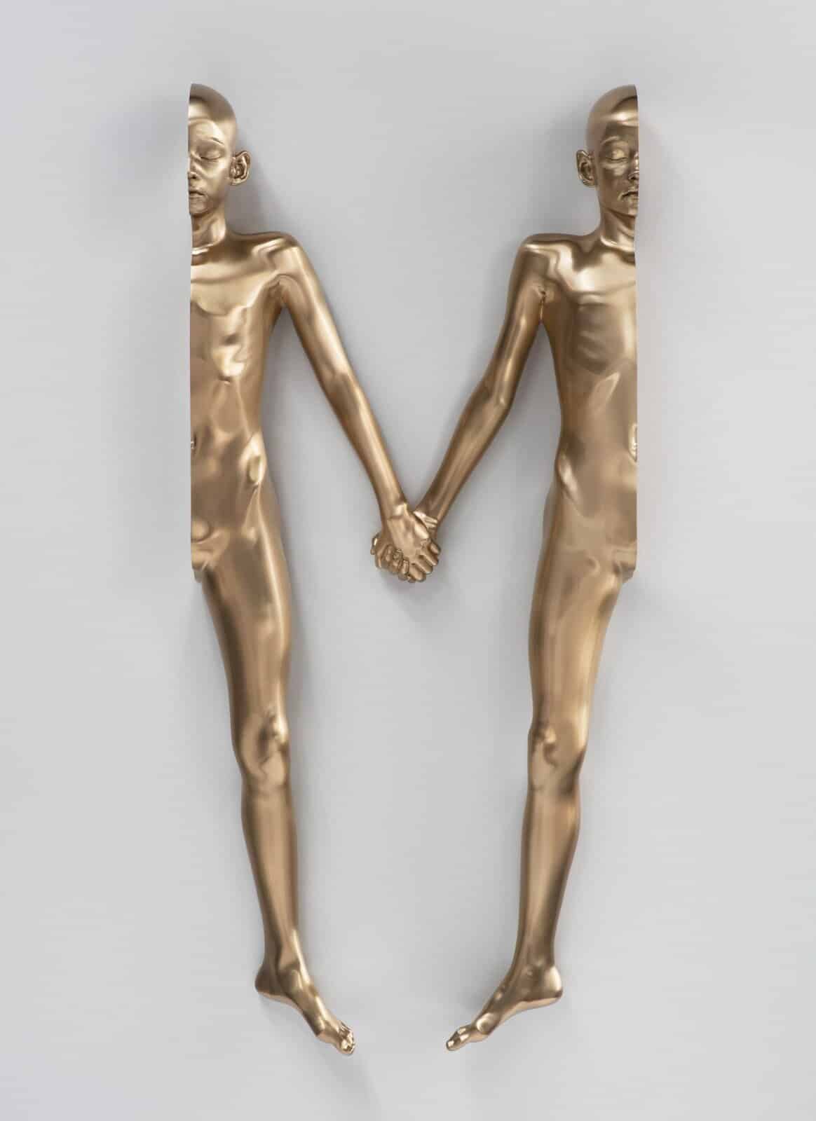 Gold metallic human figures holding hands art installation.