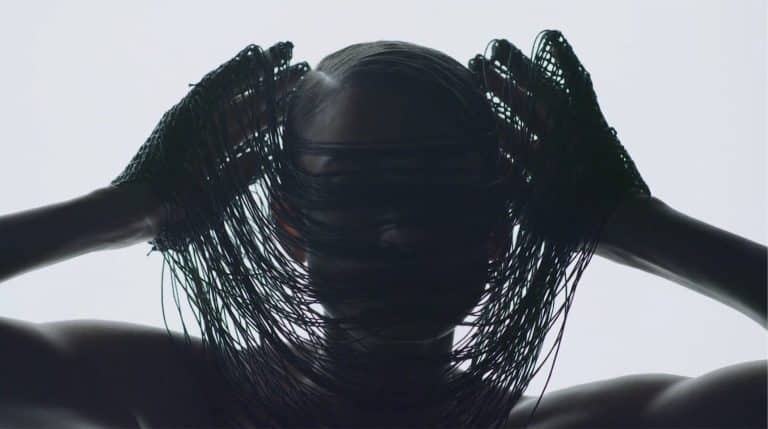 “On View” Explores The Phenomenon And Surveillance Of Capitalism Shiny black hair with a netted headpiece, artistic fashion photography.