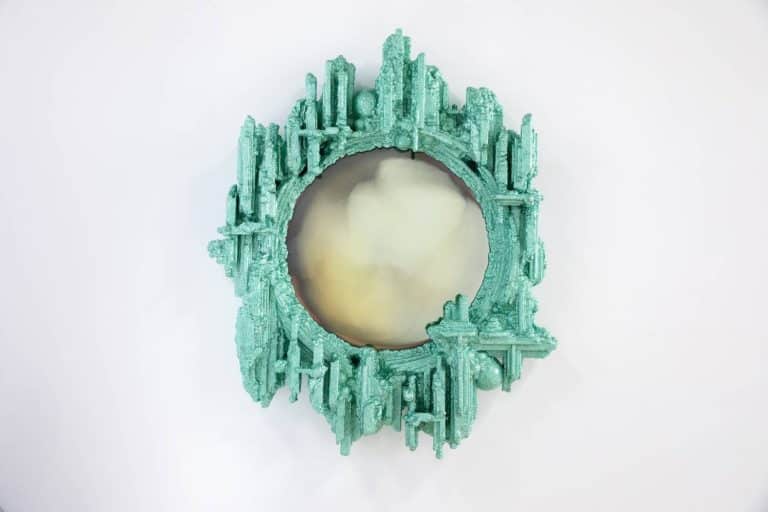 Chris Schanck Embraces Controversies And Contradictions Intricate turquoise mirror with a futuristic cityscape design, modern art piece at Visual Atelier 8.