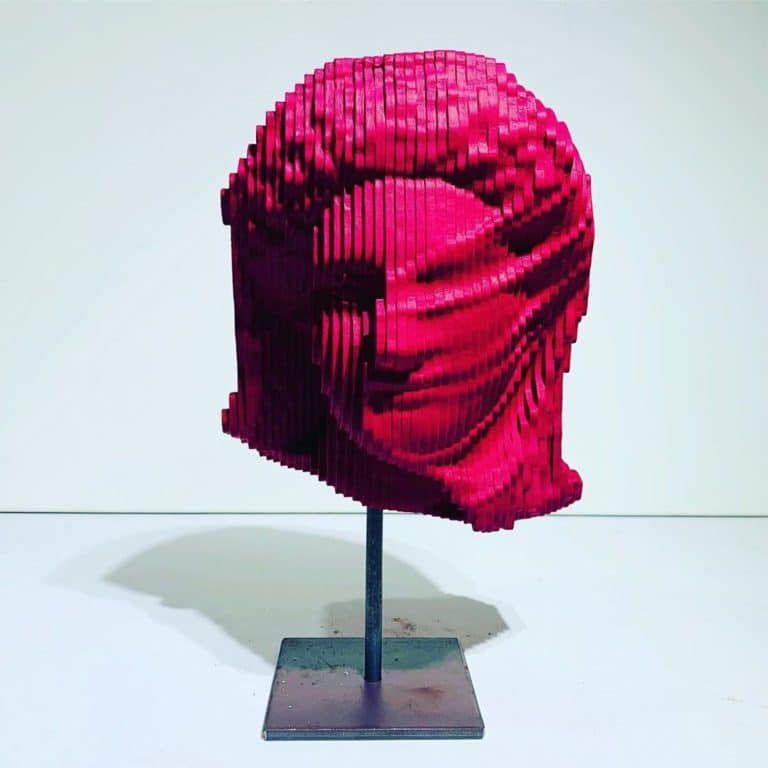 Bright Colors Of Ancient Art In Wooden Sculptures By Daniele Fortuna Colorful modern abstract sculpture made of stacked pink bricks on a metal stand, contemporary art display.