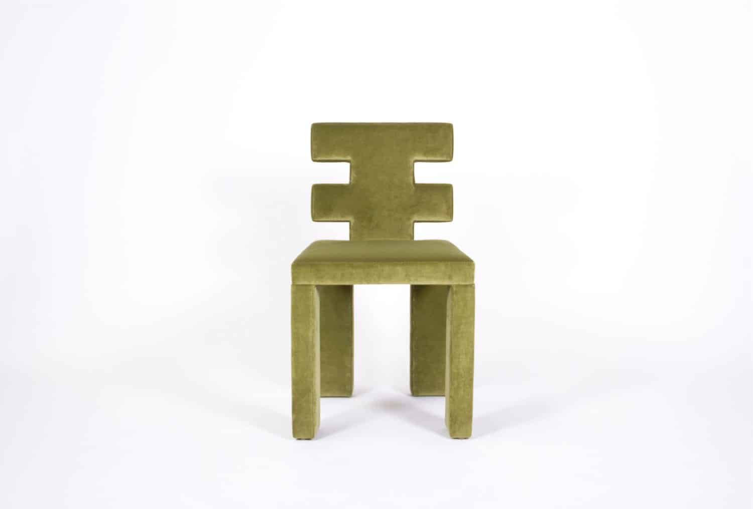 Green velvet modern chair with geometric backrest in minimalist style.