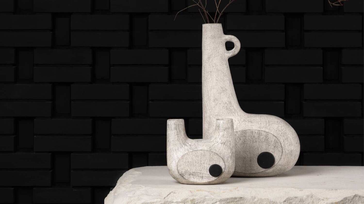Sculptural ceramic giraffe and elephant decor pieces with black circular details on textured white surface.