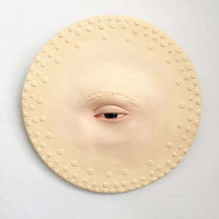 Fiona Roberts Mouths Off With Her Beautiful Sculptures Unusual round sculpture with a human eye at the center and textured surface, modern art piece.