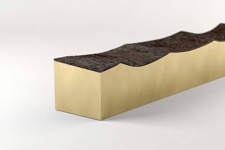 Terrestre By Gaspard Graulich Reveals The Memory Of Landscape Dark asphalt shingle cross-section on gold display block, close-up view.