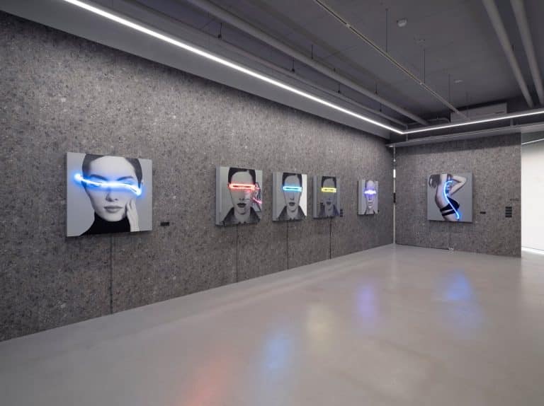 Javier Martin Dreams Up Vivid Neon Installations Colorful neon light art installation featuring black and white portraits in contemporary gallery.