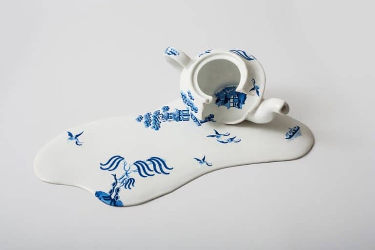 Livia Marin Sculpts And Creates Melted Fine China Elegant porcelain teapot with blue traditional Asian motifs, spilling tea and artfully designed.