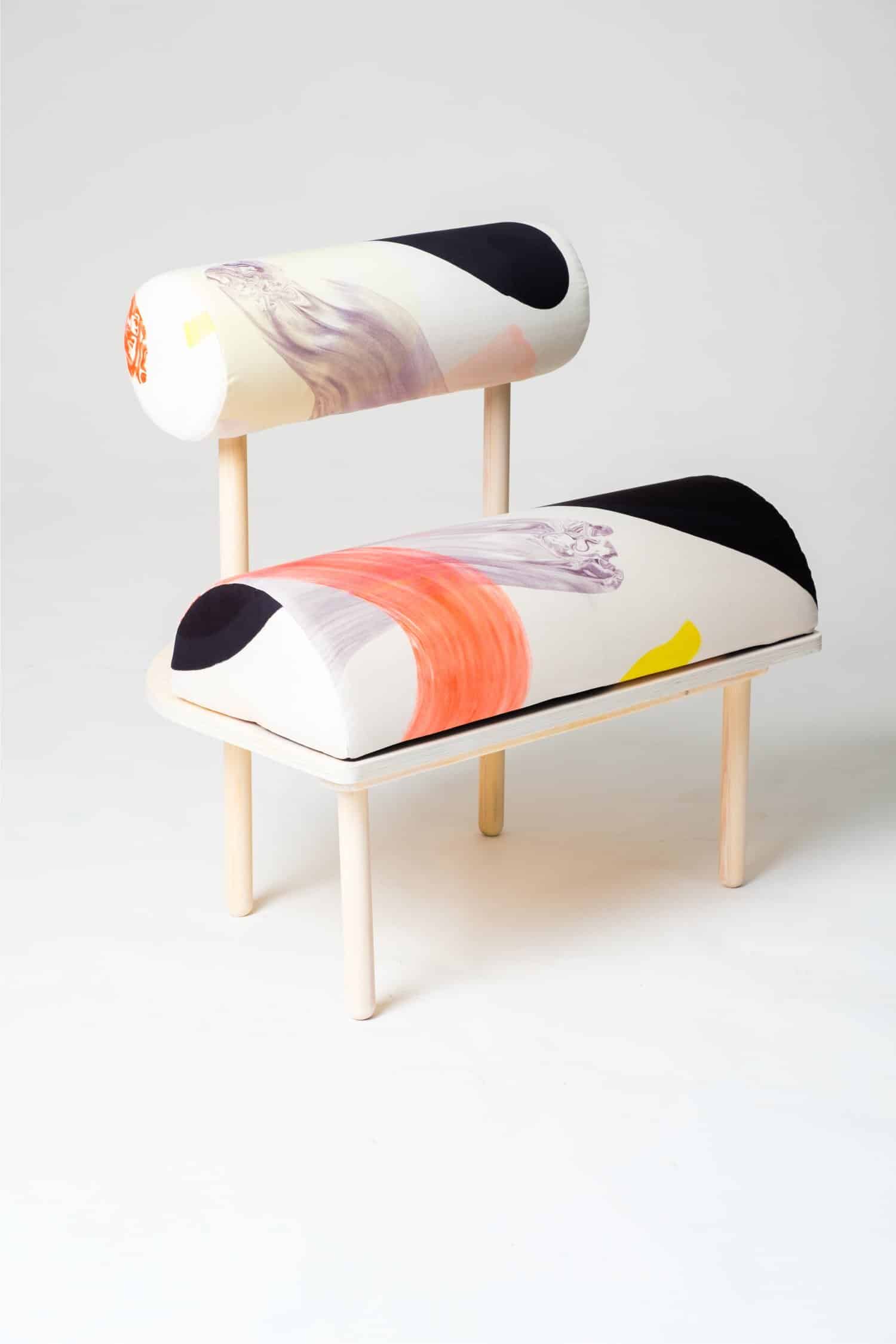 Colorful modern art chair with abstract painted cushions, minimalist design, wooden frame.