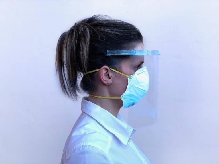Face of a woman wearing a protective face mask and face shield for health safety.