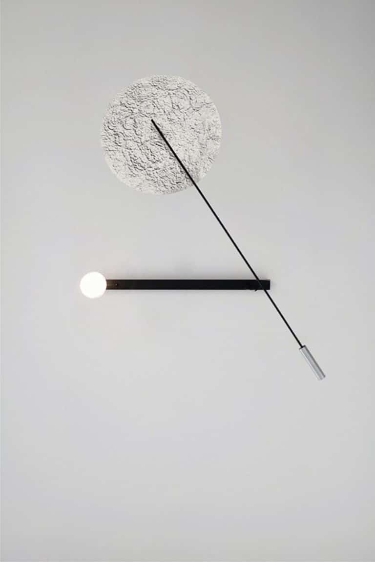 Studio Elementaires Embodies The Intersection Of Design And Art Minimalist modern wall clock with textured circular face and sleek black and silver design.