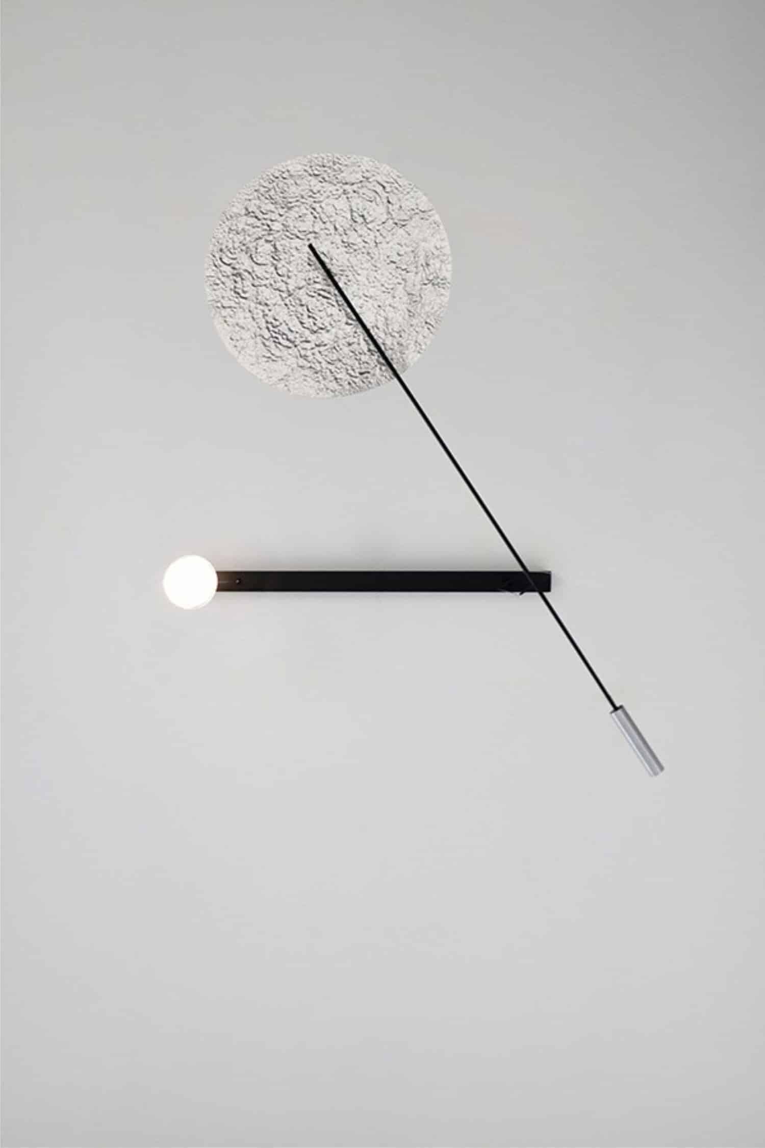 Minimalist modern wall clock with textured circular face and sleek black and silver design.