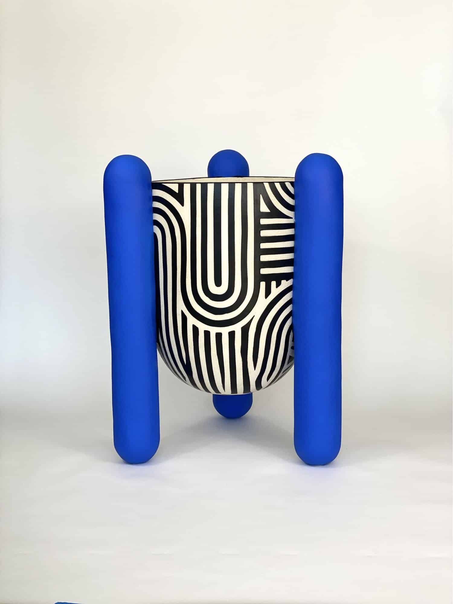 Colorful modern art sculpture with bold blue cylindrical legs and black and white striped abstract design.