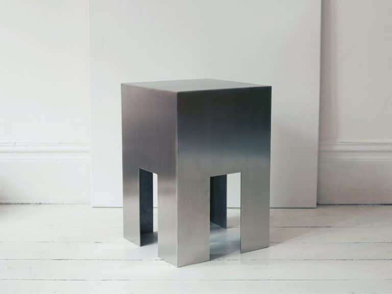 Viviana Fagnani Experiments With Spatiality Through The Metallo Series Sleek modern stainless steel stool with geometric design and minimalist aesthetic.