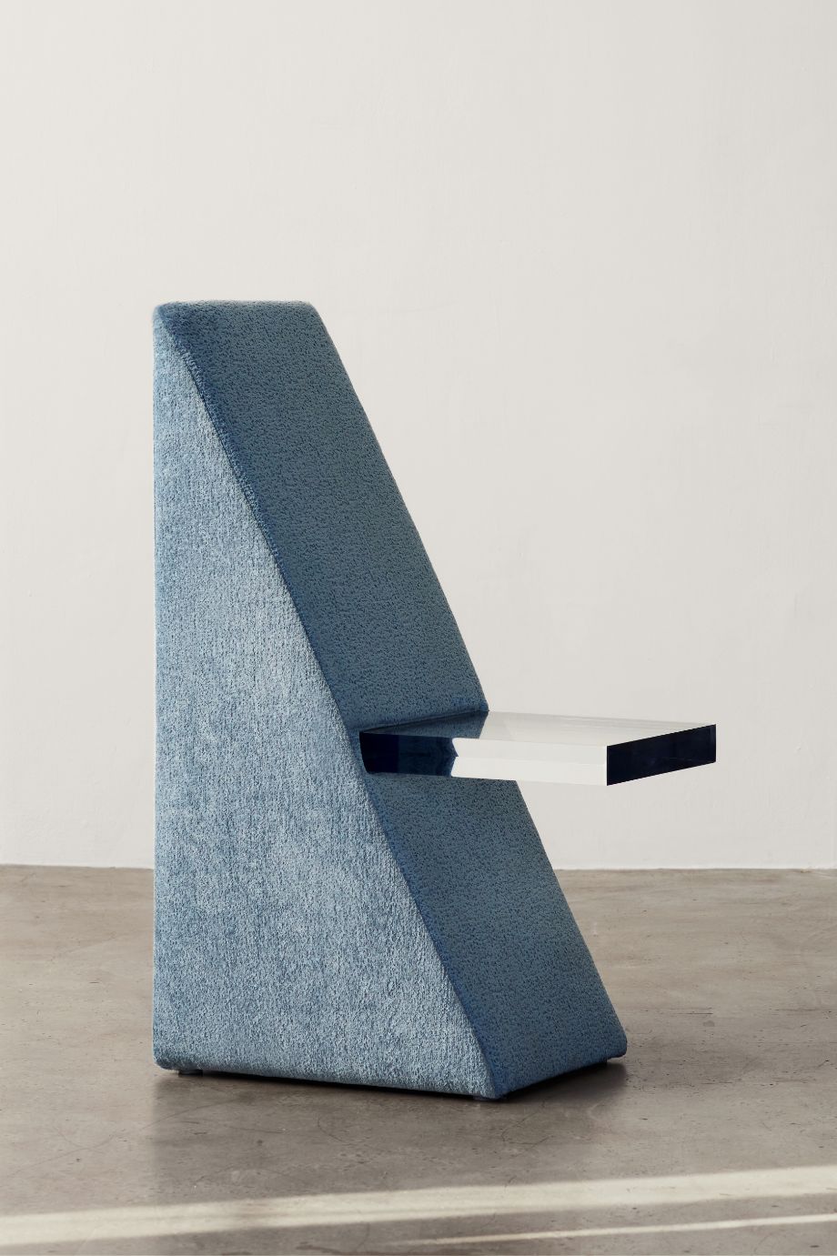 Contemporary sculptural chair with textured blue fabric and sleek white floating seat.