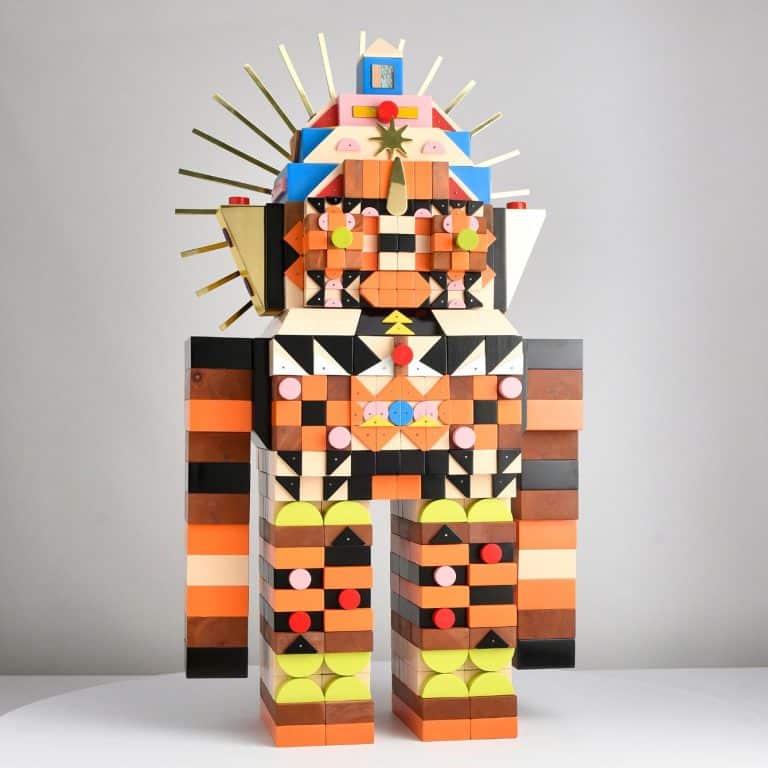 Kumkum Fernando is Crafting Timeless Art from Cultural Heritage Colorful geometric wooden sculpture of a robot with vibrant shapes and patterns.