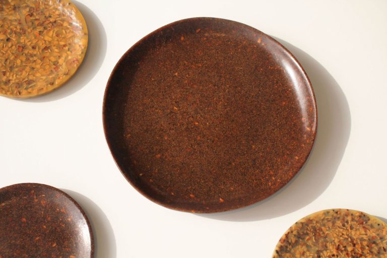 NOS by Sooa Choi: Innovative Sustainable Tableware Utilizing Walnut Shells Glossy brown ceramic plates on white background, modern minimalist tableware design.