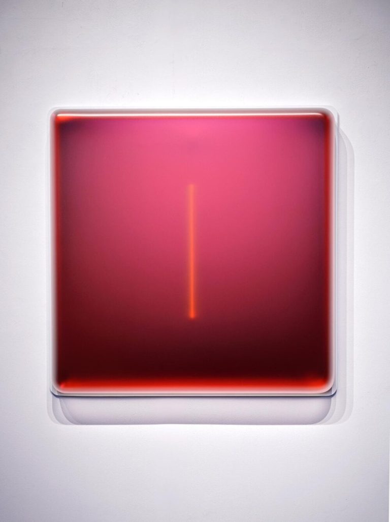 An interview with Casper Brindle, Master of Light, Color, and Sensory Exploration Sleek red square wall art with glowing LED light in a modern art display.