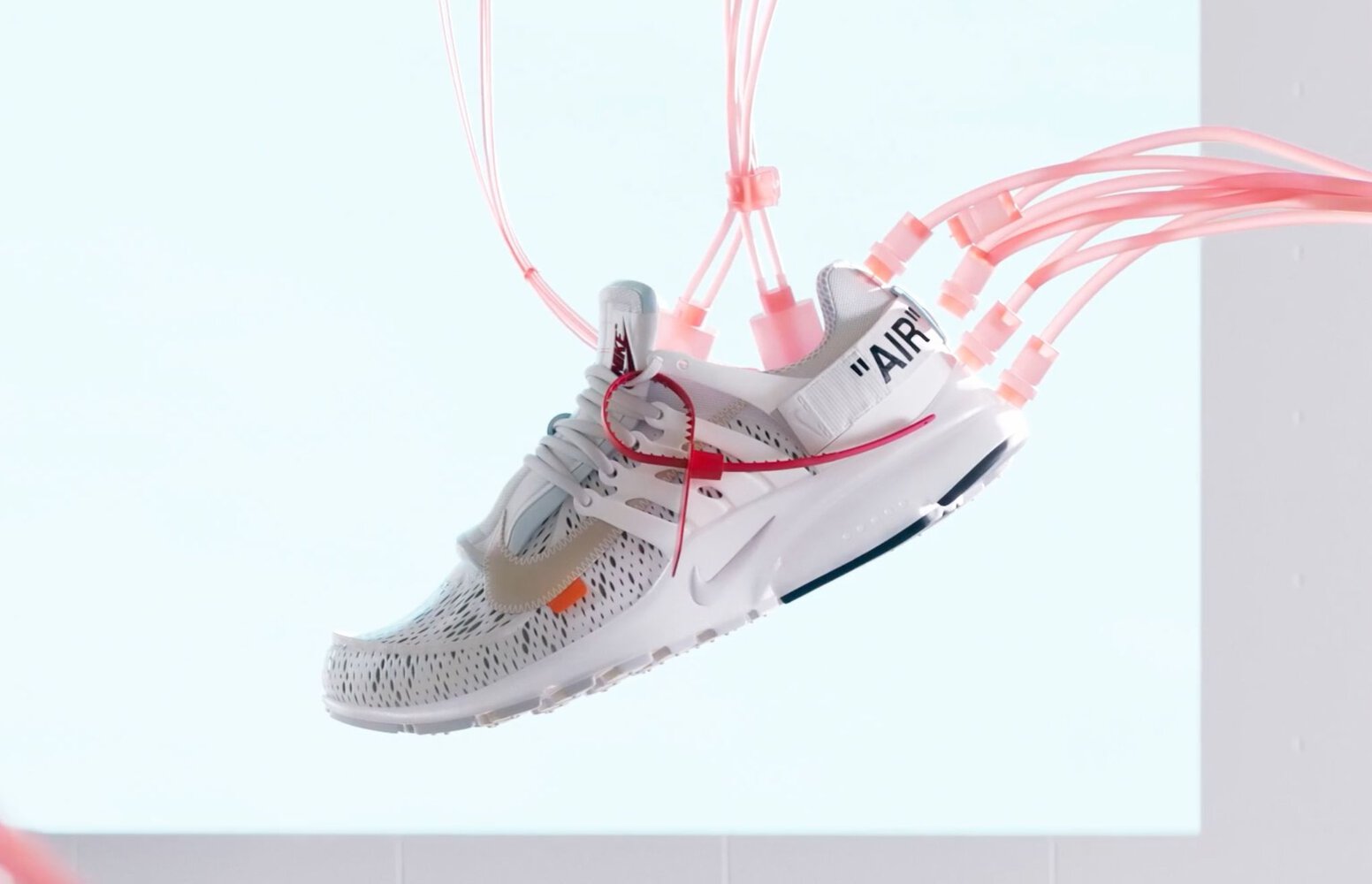 Futuristic white sneaker with pink tubes and laces, modern design, inspired by high-tech fashion and innovation.