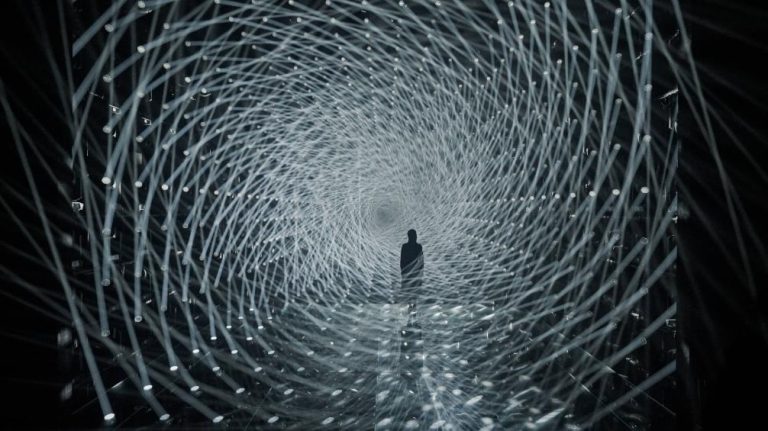 Unveiling teamLab Borderless mesmerizing exhibition in Tokyo Futuristic light installation with dynamic LED tunnels and a solitary person walking through, creating an immersive experience.