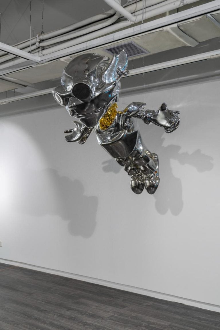 Tairan Hao's Artistic Odyssey Blending Identity, Technology, and the Virtual Realm Shiny metallic sculpture of a stylized animal figure hanging from ceiling at Visual Atelier 8.
