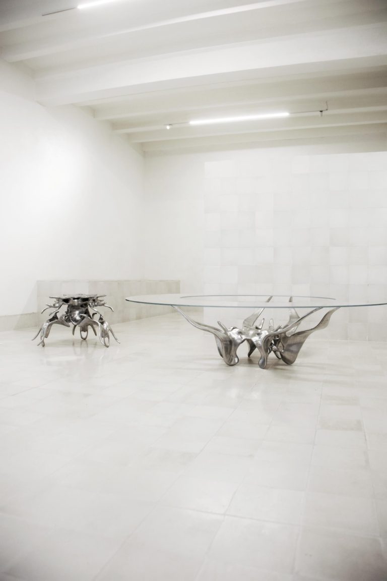 ERM Studio's "Materia Digital" Collection: A captivating fusion of digital technology and artistic expression Elegant metallic sculptural furniture piece in a minimalist gallery space, modern art design.