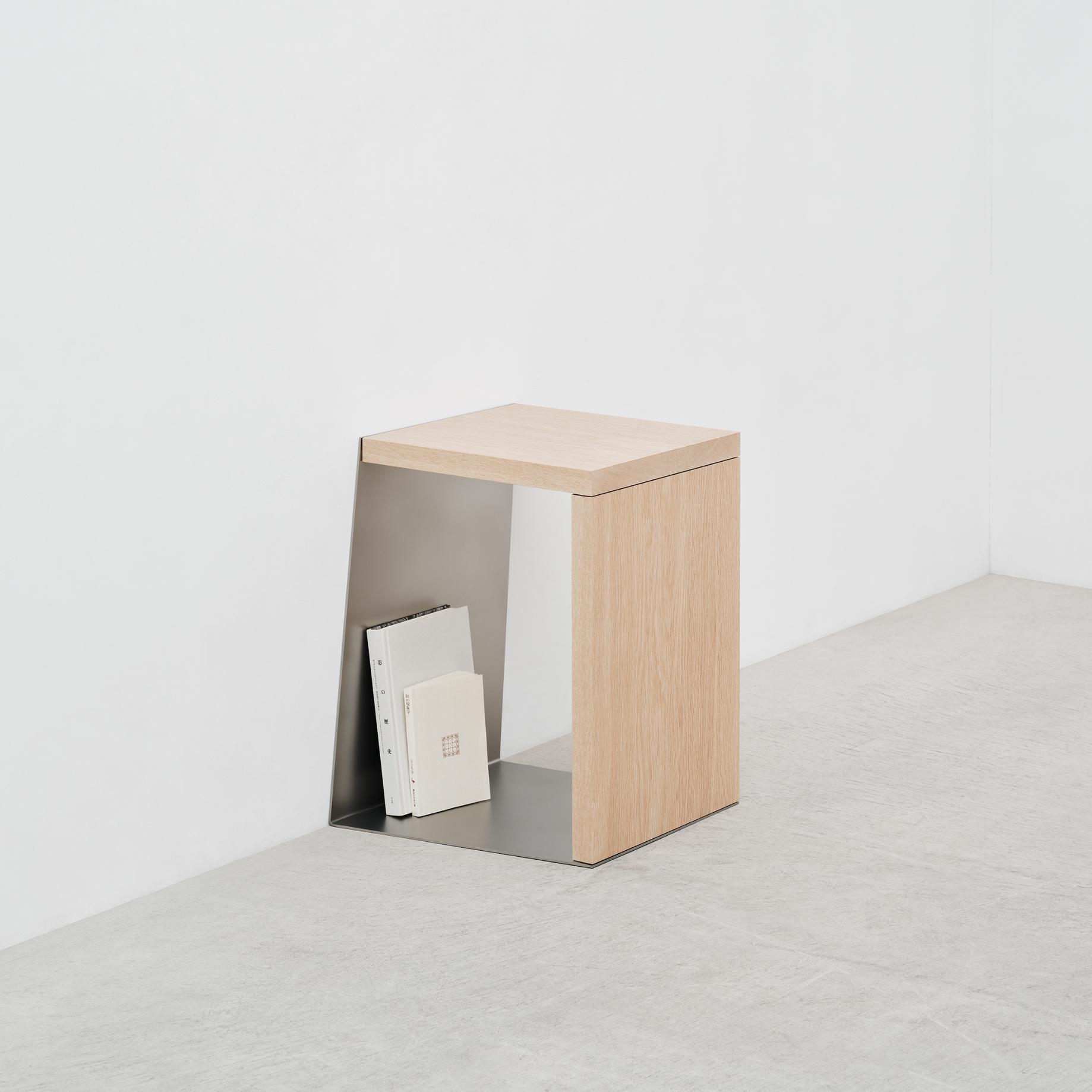 Minimalist wooden side table with metal interior shelf holding books, modern decor.