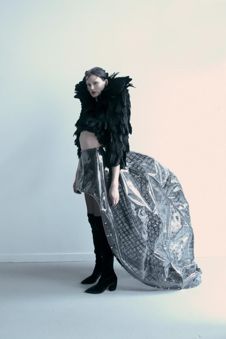 Feathered black crop top with metallic skirt and high boots fashion photoshoot.