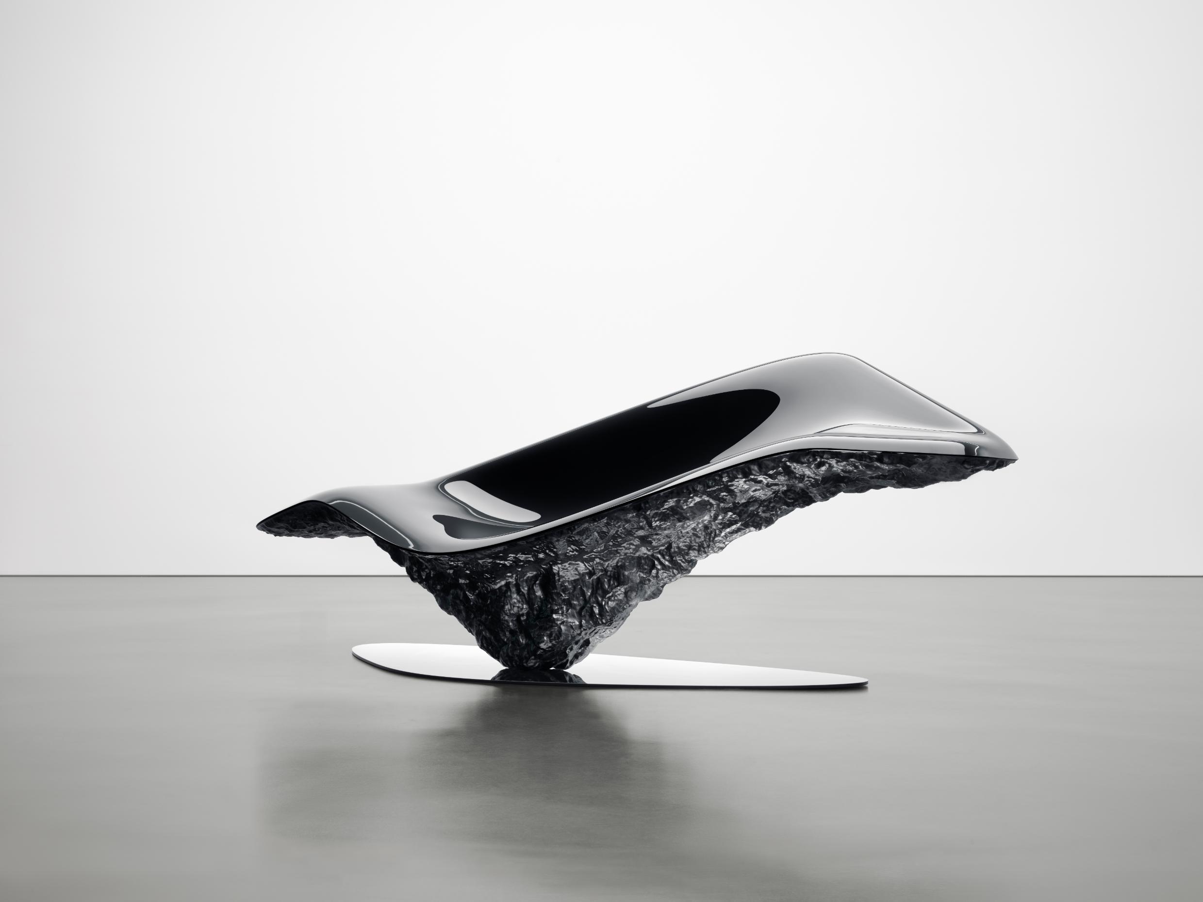 Sleek futuristic concept car with a high-gloss black finish on a textured black base.