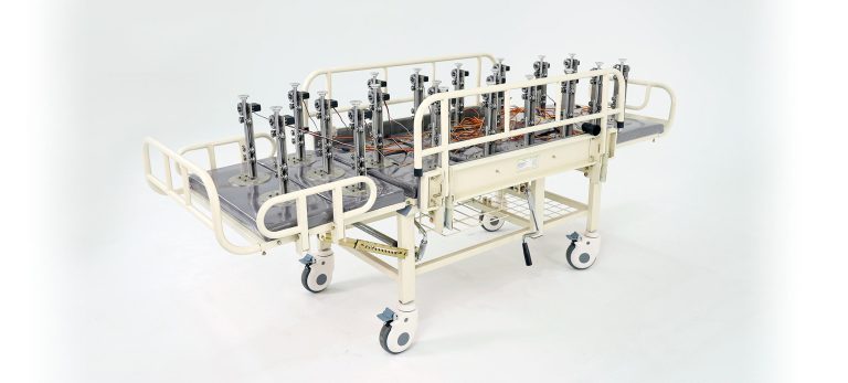 Bridging Life and Art in Di Tian's 'Mother / Father' Interactive Installation A hospital stretcher with medical equipment and wires, designed for patient care and transportation.