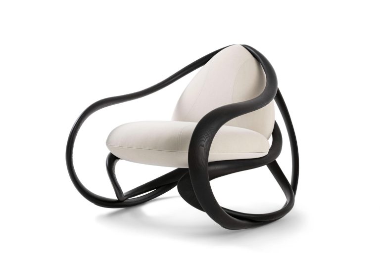 The MOVE rocking chair is drawing inspiration from the organic forms Contemporary modern armchair with black sculptural wooden frame and white upholstered cushion.