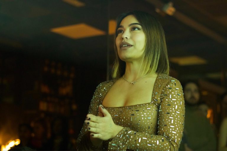 Elegant woman with shoulder-length hair wearing a sparkling brown dress at a social event.