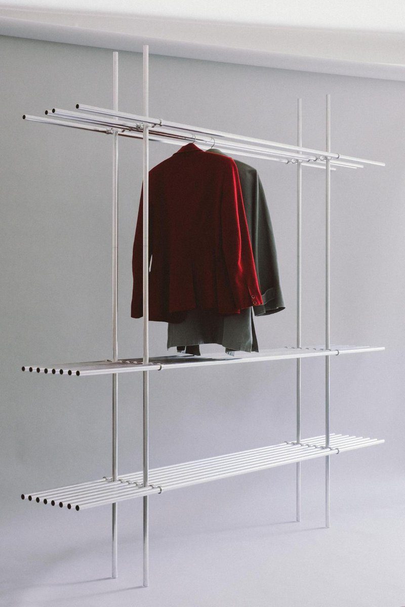 Sleek modern clothing rack with hanging jacket and blazer, minimalistic design for stylish retail or home organization.