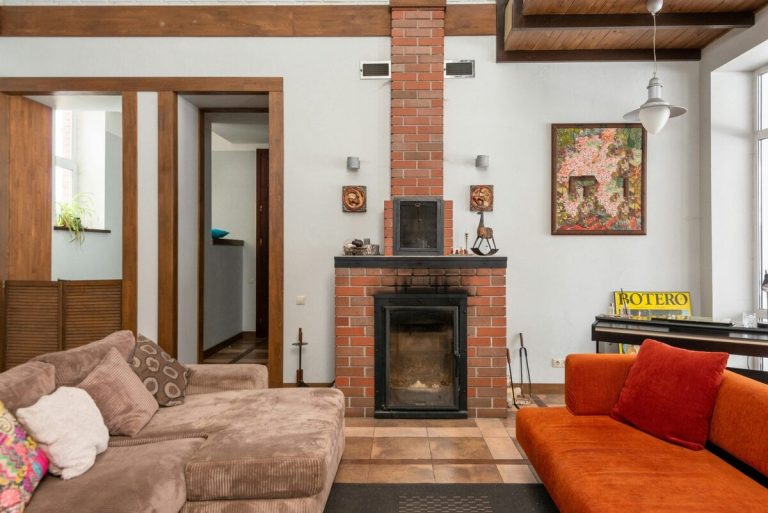 Magnolia Home by Joanna Gaines: A Cozy Style That Marries the Unique and the Unexpected Cozy living room with brick fireplace and colorful artwork for stylish home interior.