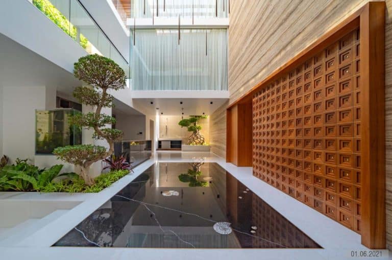 Modern architectural space with water feature, wooden wall, glass panels, and minimalist landscaping.