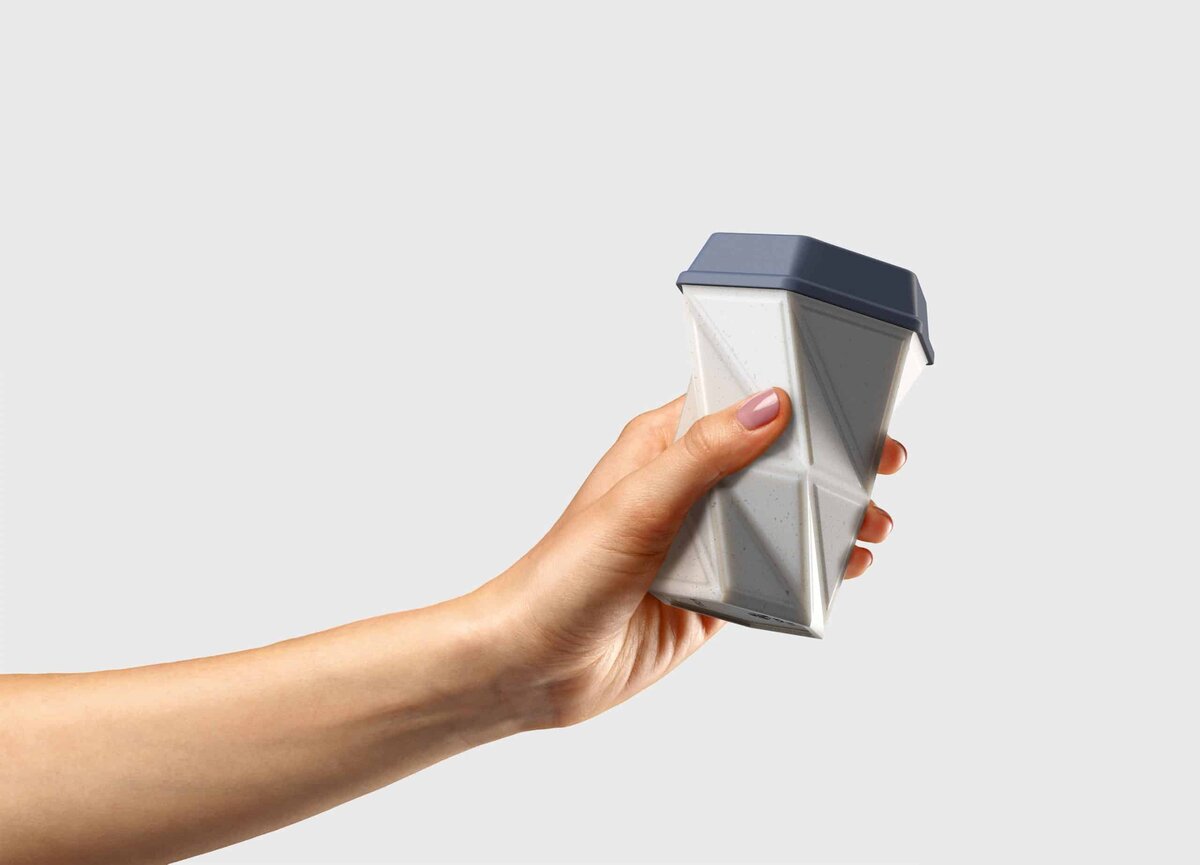 Modern faceted coffee cup with dark blue slanted lid for easy grip.