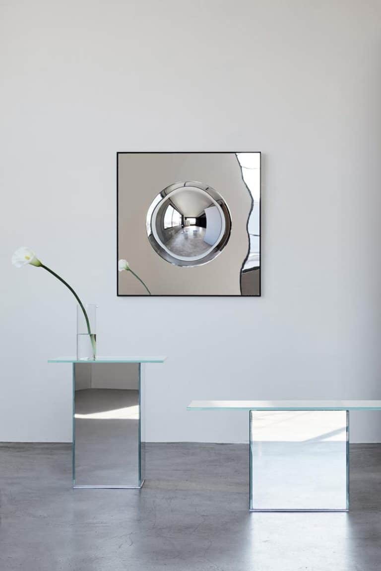The Orb Wall Mirror Is An Artistic Exploration of Perception Shiny round washing machine with modern minimalist decor in a boutique showroom or gallery.