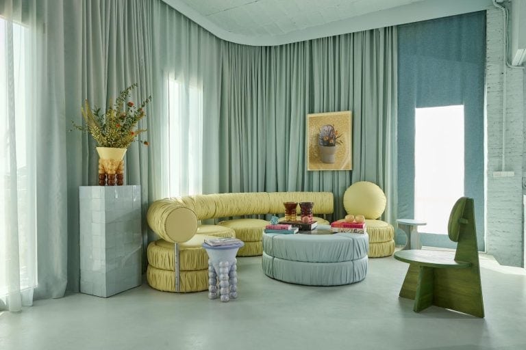 An interview with Masquespacio on their distinctive and innovative aesthetics Colorful modern living room with eclectic furniture, light blue accents, and decorative elements.