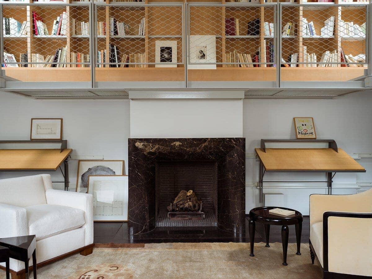 Modern living room with white sofa, dark table, and marble fireplace.