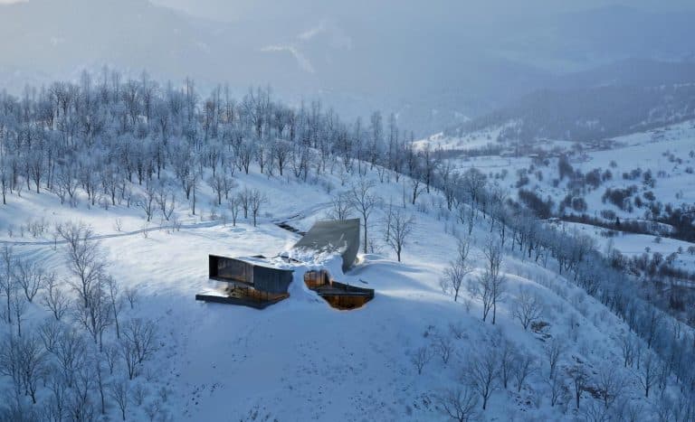 Snøhetta’s "NOT A HOTEL": A Harmonious Sanctuary Overlooking Mount Yotei Snow-covered modern house with large glass windows in a mountainous winter landscape.