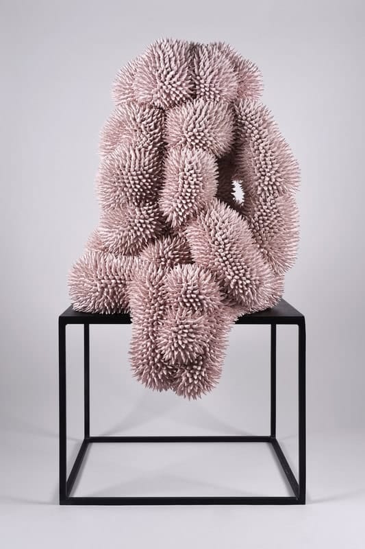 Ceramic Artist Andres Anza on His Unique and Abstract Creations Soft pink textured sculpture resembling coral or abstract art on black table.
