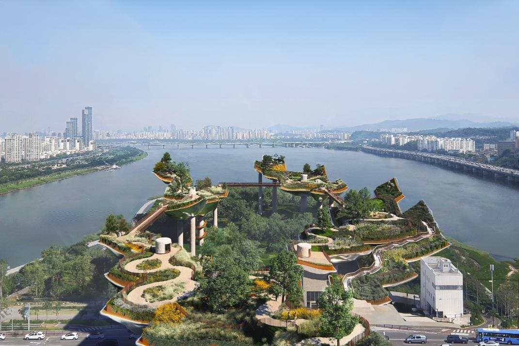 Aerial view of a modern eco-park with green terraces and city skyline in the background.
