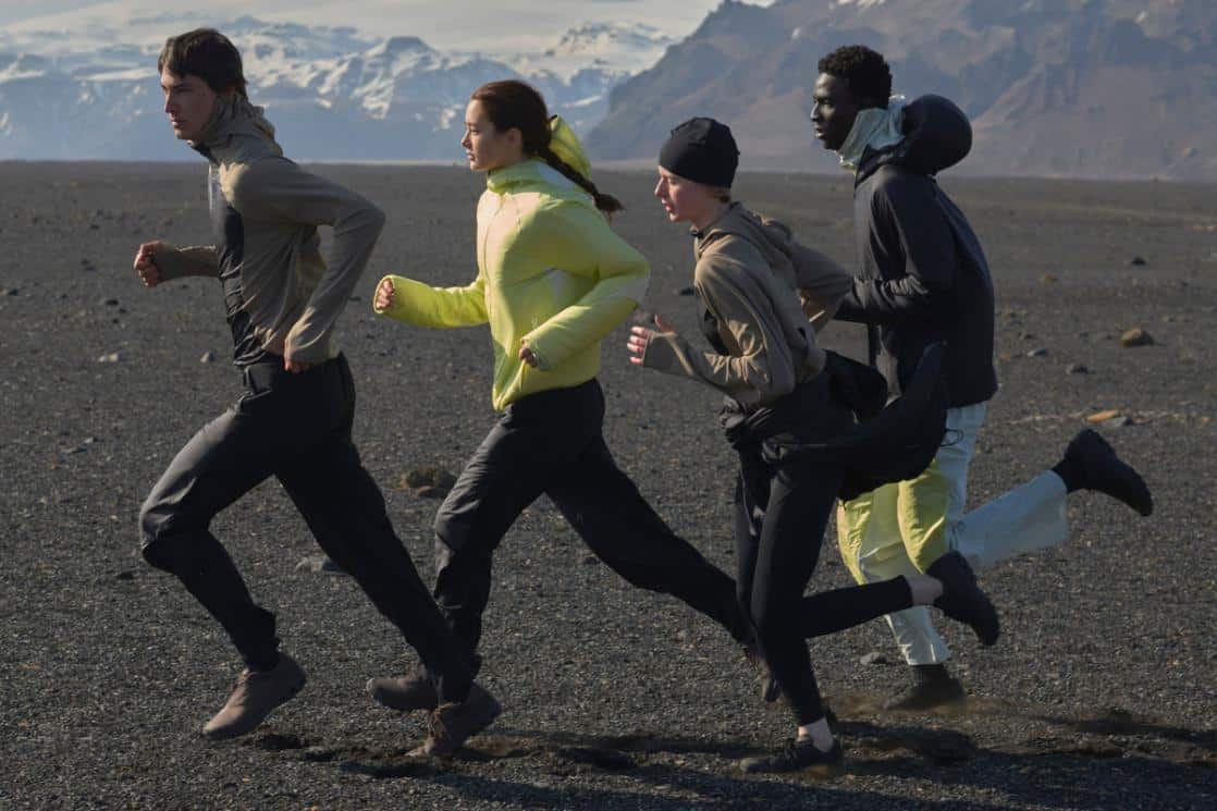 Young diverse group running outdoors in outdoor sportswear, scenic mountain landscape, adventure activity, fitness lifestyle.
