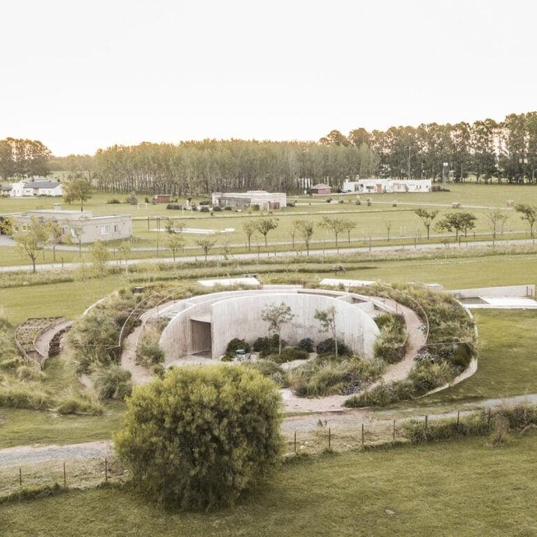 The Shire House by AtelierM redefining eco-friendly living Futuristic concrete eco-home with curved design surrounded by greenery in a rural setting.