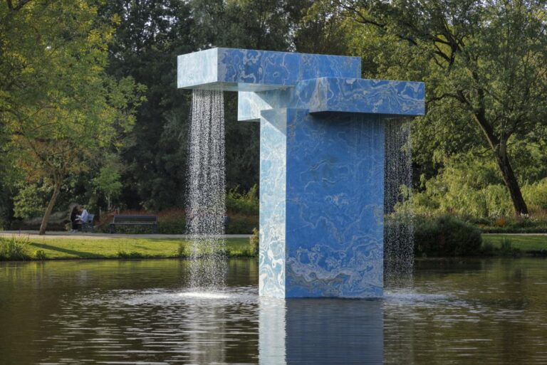"Vondel Fountain, Stacked": SolidNature And Sabine Marcelis' Monumental Installation Marble water fountain sculpture in a park setting, surrounded by lush trees and greenery.